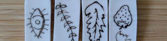 A close-up of 4 test tiles with clear glaze and black underglaze detail.